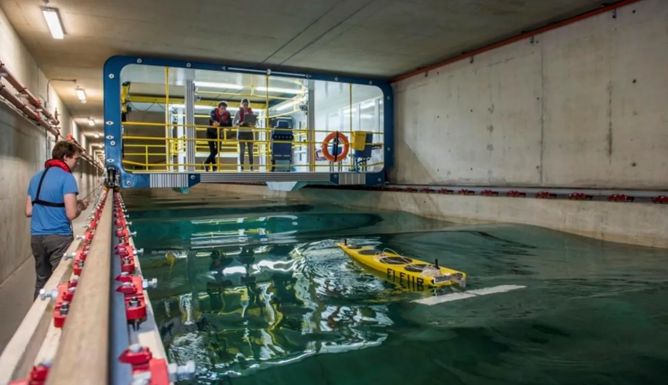 Three students test a model boat in the towing tank