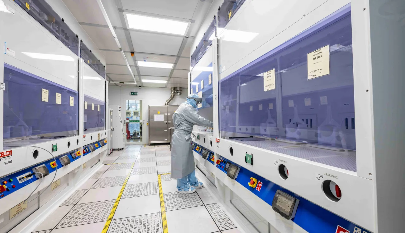 A researcher in a cleanroom suit using the acid wet benches in the nanofabrication cleanroom