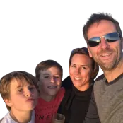 Clinical Trial participant Crispin smiling in sunlight with his wife and two sons