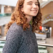 Applied GIS and Remote Sensing master' s student Jessica is standing on a balcony in a building smiling at the camera