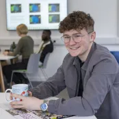 Samuel sat at a table in a communal area smiling for the photo.
