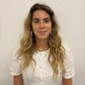 A headshot of a student with long blonde hair, wearing a silver necklace and a white top.