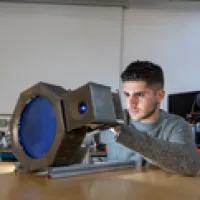 A student working on a piece of equipment in a design studio