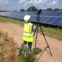 A student conducting fieldwork beside a large bank of solar panels
