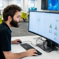 Male computer science master's student sitting at a workspace on a computer 