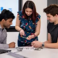Three computer science students working with a motherboard of a computer