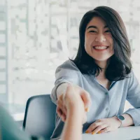 Women shaking hands over a desk
