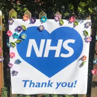Thank you NHS sign decorated with flowers on garden gate.