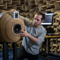A student positioning a novel, spherically-designed speaker system inside the large anechoic chamber for testing.