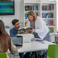 A lecturer teaching law students with laptops and text books in small groups