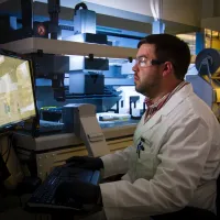 A man in lab sitting in fromt of a computer.