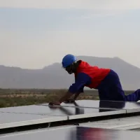 person wearing construction clothing fitting solar panels for renewable energy on roof in kenya