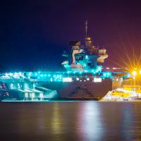 Aircraft carrier lit up at night in dock