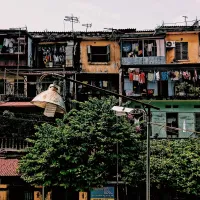 A black lampost with the light turned off in front of intensive tiered housing