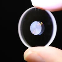 A small optical lens held between a finger and thumb