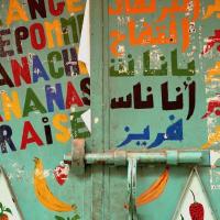Closed metallic door of a shop with coloured words in French and Arabic about juices