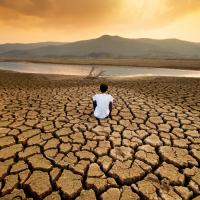 A man sit on dry land in an empty lake
