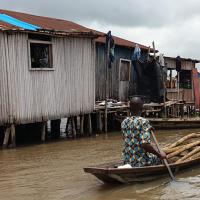 A resident of Ganvie stilt village in Benin navigates a boat through water