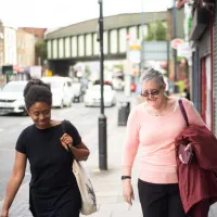 2 women talking as they walk down a street