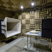 Anechoic chamber interior with foam panels, a large speaker, and a metal table with an object.