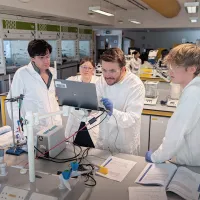 Several students in laboratory looking into the computer screen