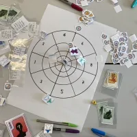 A tabletop game in progress showing cards, tokens and a target board used for exploring character, emotion and decision-making.
