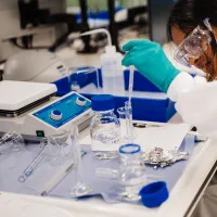Student wearing safety goggles uses a pipette during a biomedical engineering lab experiment.