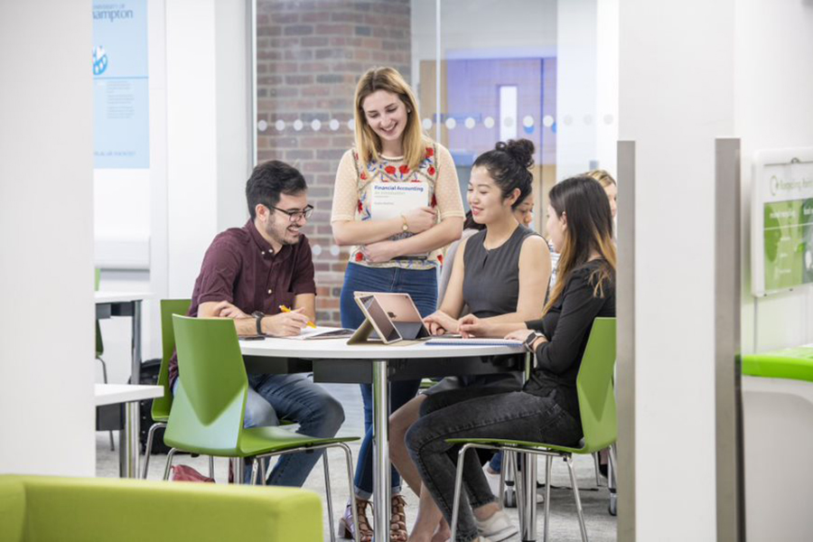 Four business students sitting around a table discussing their work