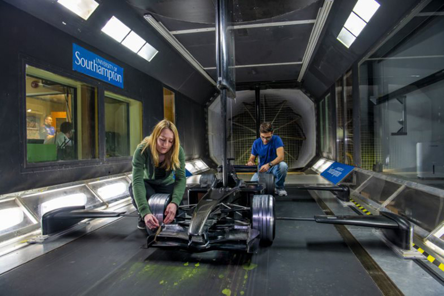 Two students work on a race car in one of the wind tunnels
